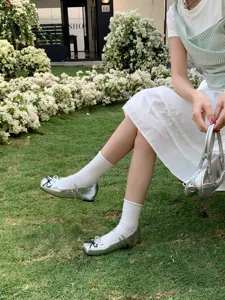 Close-up detail of silver metallic Mary Jane shoes with double straps and cute bow.