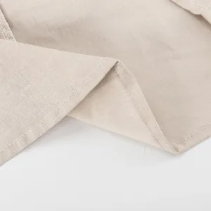 Close-up detail of women's beige cotton linen dress hem, fine stitching texture display.