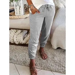 Detailed shot of casual gray drawstring trousers in a cozy home living room setting.