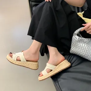 Nahaufnahme von Damen-Keilsandalen aus Stroh in Beige mit schickem H-Riemen-Design.