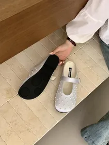Close-up detail of french fairy style satin pearl mule slippers, elegant flat slip-on shoes.