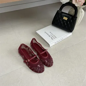 Close up view of burgundy beaded flat shoes featuring delicate embroidery and strap.