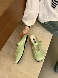 Close-up detail shot showcasing light green satin mules with exquisite pearl decorations.
