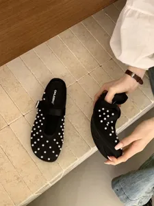 Detailed view of black satin pearl mules, featuring elegant pearl embellishments and strap.