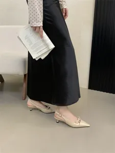 Vista detallada de elegantes zapatos slingback beiges con punta afilada y lazo delicado.