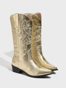Primo piano di stivali da cowboy dorati metallizzati con punta affilata e ricamo.