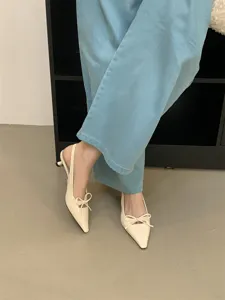 Primer plano de elegantes zapatos destalonados de punta con un precioso lazo chic.