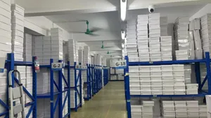 Magazzino industriale con scatole per scarpe bianche impilate ordinatamente sugli scaffali.