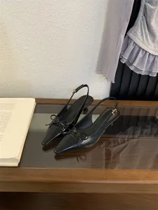 Primer plano de elegantes zapatos negros destalonados de tacón bajo y fino con bonito lazo.
