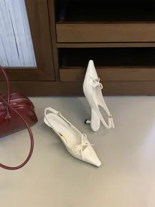 Detalle de unos elegantes zapatos de tacón destalonados con punta fina y un lazo delicado.