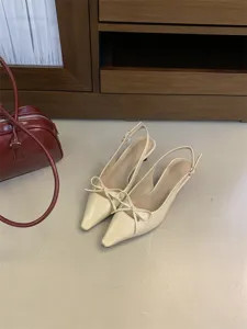 Zapatos de tacón destalonados en beige con punta fina, elegante lazo y tacón fino.