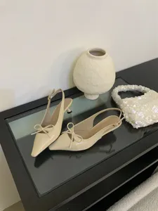 Vista detallada de elegantes zapatos slingback beige con tacón bajo y lazo bonito.