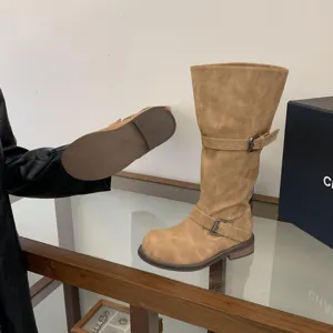 Retro distressed knee-high motorcycle boots for women featuring chunky heel and buckle straps.