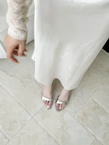 Silver metallic open-toe high heel slip-on sandals detail shot, stylish and elegant footwear.