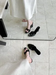 Detail shot of elegant black patent leather wedge sandals, showing open toe and chic style.
