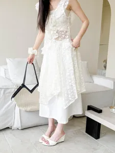 Detail shot of stylish open-toe wedge sandals paired with elegant lace outfit indoors.