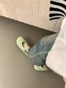 Detail shot of light green satin mules featuring delicate pearl embellishments and chic straps.