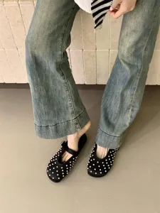 Detail view of black satin mules with pearl embellishments, showcasing texture and slip-on style.