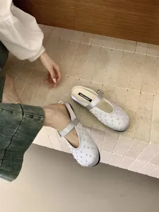 Detail view of elegant satin pearl mules, showcasing delicate embellishments and soft texture.