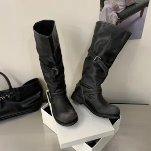 Black distressed knee-high motorcycle boots with chunky heels and stylish metal buckle straps.