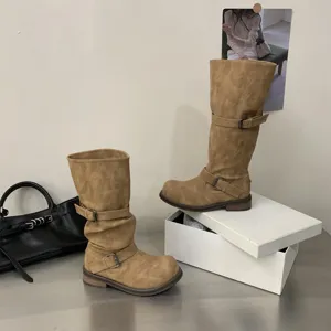 Detail shot of vintage slouchy motorcycle boots in camel color featuring stylish dual buckle straps.