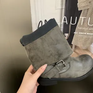Detail view of vintage distressed leather motorcycle boots with buckle and fold-over cuff.