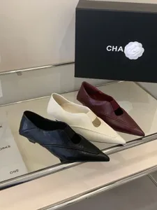 Vista detallada de elegantes zapatos planos de punta en tres colores sobre estante.