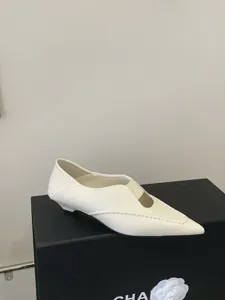 Detalle en primer plano del zapato blanco de tacón bajo con puntera puntiaguda fina.