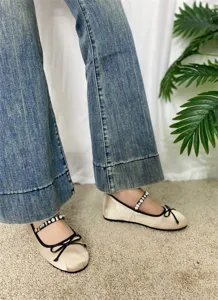 Primo piano di scarpe Mary Jane in raso con cinturino di strass ed elegante fiocco nero.