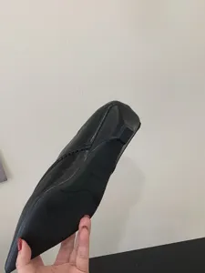 Detalle de la suela plana de zapatos negros de punta mostrando textura y la talla.