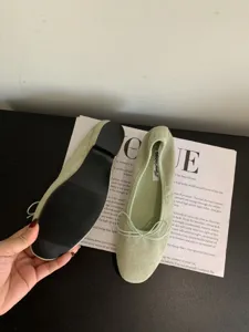 Primer plano de la suela y lazo de bailarinas de terciopelo verde sobre revista retro.