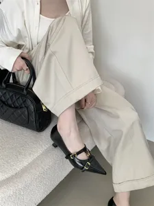 Close-up of black pointed-toe kitten heels with chic double buckle straps worn by a model.