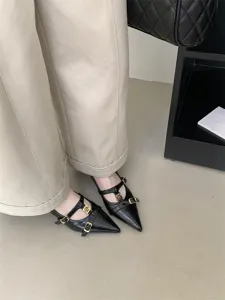 Black pointed-toe kitten heels with T-strap design and chic metallic buckles for women.