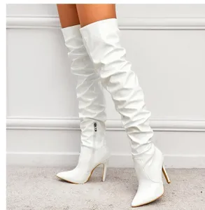 Close-up of white patent leather over-the-knee boots, pointed toe, slim high heel, zipper detail