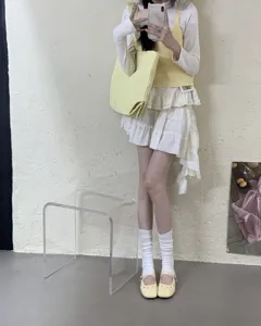 Detailansicht stilvoller gelber flacher Mary Jane Schuhe mit weißen Socken und Rock.