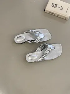 Silberne metallic Plissee Thong flache Sandalen Detailansicht, minimalistischer Stil.