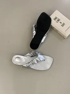 Silberne geraffte flache Zehentrenner Detailaufnahme, zeigt das schicke Riemendesign.