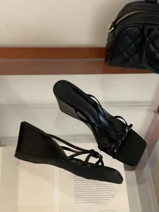 Gros plan détaillé de sandales mules noires à talons compensés et brides fines carrées.