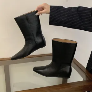 Detail view of black leather mid-calf boots with square toe and flat heel design.