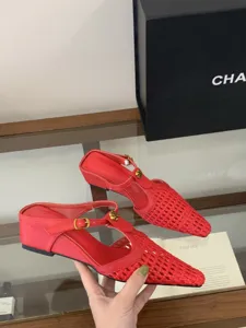 Primer plano detallado de los zapatos mules con cuña tejida roja y hebilla de flor de metal.