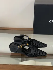 Mules negras de punta con cuña, empeine trenzado y elegante hebilla floral dorada brillante.