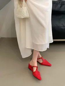 Primer plano de zapatos mules planos tejidos rojos con punta fina, estilo francés.