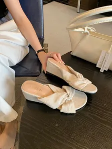 Gros plan de sandales compensées en lin beige à brides croisées, texture et design élégant.