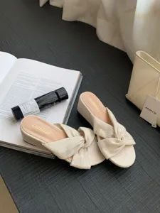 Sandales mules compensées nouées en lin beige détail bout ouvert et talon confortable.