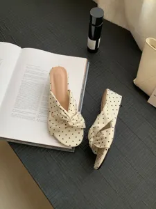 Vue detaillee de sandales compensées beiges à pois avec brides croisées et bout ouvert.