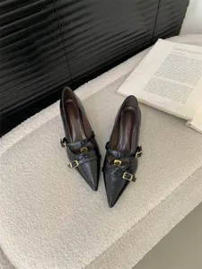 Detail shot of elegant black pointed-toe kitten heel pumps with double straps and gold buckles.