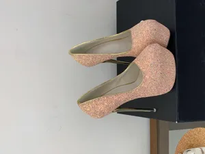 Glitter platform stiletto heels detail, sparkly pink high heels with gold trim close up view.