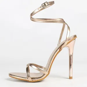 Metallic champagne high heel sandals with thin straps and elegant ankle wrap design.