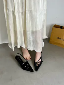 Black patent leather pointed toe slingback kitten heels with delicate strap and buckle details.