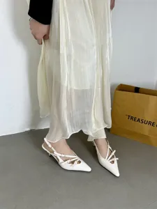 White patent leather slingback kitten heels with chic crossover straps and pointed toe detail.